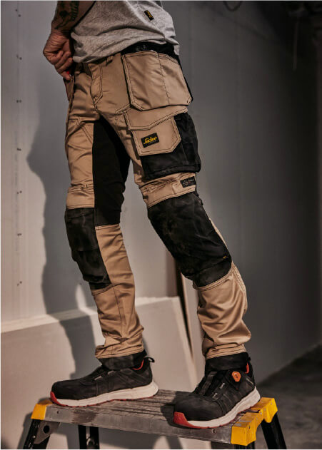 Snickers werkbroek khaki model op ladder met gereedschap bij de hand